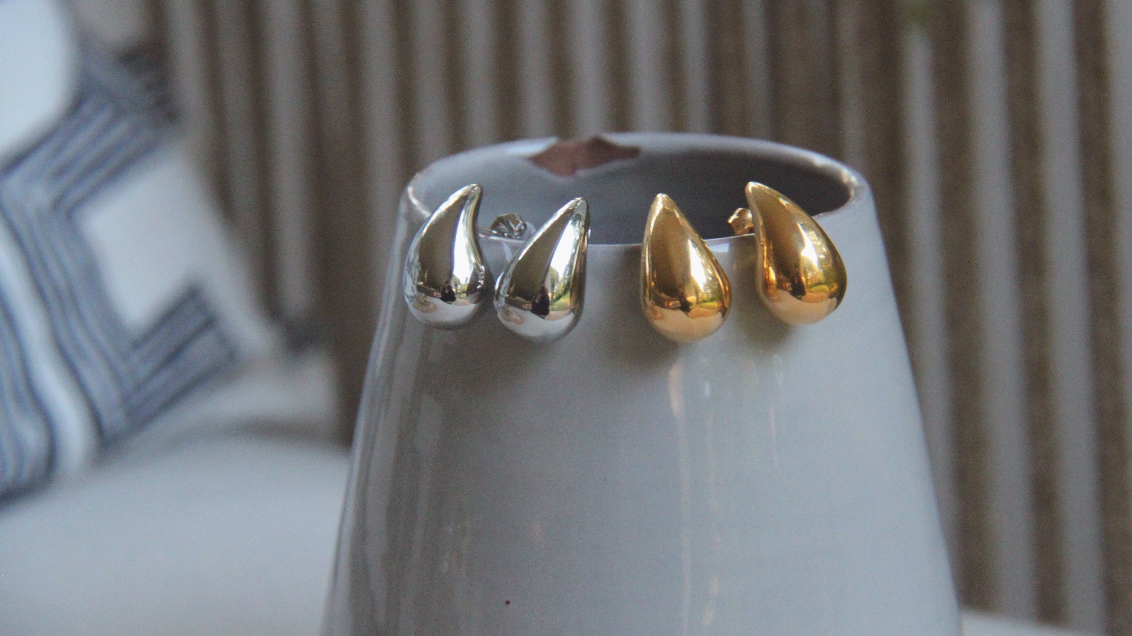 Gold and silver spike earrings on a gray surface with a blurred background